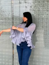 Blusa color gris con volados en las mangas y en el ruedo.