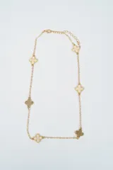 Collar de cadena dorada con dijes en forma de trébol de cuatro hojas, alternando entre piezas con centro esmaltado en color crema y piezas con textura metálica.