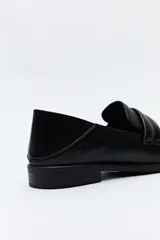 Mocasín negro de cuero sintético con punta cuadrada, detalle de textura en la capellada y taco bajo de 2,5 cm.