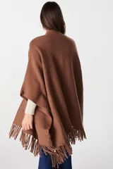 Ruana de tejido suave y envolvente en color blanco, con diseño de corte amplio y terminación de flecos en el ruedo.