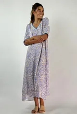 Vestido largo con estampado animal print en tonos lila y beige, con cuello en V y mangas cortas con puños.