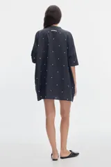 Vestido corto de algodón con estampa de lunares, cuello mao y cierre frontal con botones. Presenta un diseño holgado de mangas cortas.