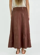 Pollera larga de lino color blanco, con corte acampanado y paneles verticales con costuras a la vista.