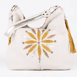Cartera tipo hobo de cuero color crudo con apliques de cuero dorado, plateado y marrón formando una flor. Tiene correa de hombro de cuero crudo con aplique plateado y detalle de flecos mostaza en el lateral. Incluye correa larga opcional para usar como morral.