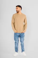 Buzo de manga larga con cuello redondo, confeccionado en tejido de punto con textura tipo waffle. Presenta un diseño minimalista con una pequeña etiqueta decorativa en el ruedo inferior.