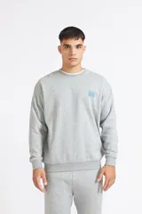 Buzo Quiksilver World Force de color gris melange, con cuello redondo y mangas largas. Presenta un pequeño estampado en el pecho con el logo de la marca en tonos verde y azul.