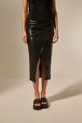 Falda midi negra de efecto cuero, con diseño cruzado tipo wrap y abertura frontal pronunciada.
