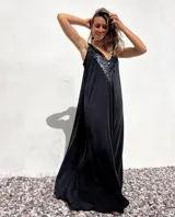 Vestido largo de corte holgado en color negro, con escote en V profundo decorado con lentejuelas negras brillantes. Presenta un diseño sin mangas y una caída fluida.