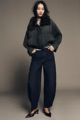 Jeans de tiro alto con corte barrel y diseño tapered, confeccionados en denim con efecto lavado y detalle de raya planchada. Presentan cintura con trabillas, cierre frontal con cremallera y botón, y bolsillos funcionales en delantero y espalda.