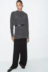 Vestido corto de tejido suave color gris oscuro, con cuello redondo y manga larga. Incluye un cinturón fino de efecto piel con hebilla metálica dorada.