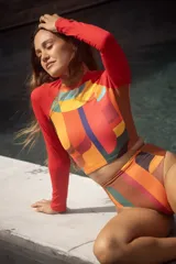 Conjunto de traje de baño compuesto por un top de mangas largas con estampado abstracto multicolor y una bombacha de tiro alto con laterales acanalados.