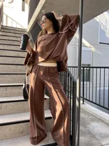 Pantalón de corte holgado color marrón, con cintura elástica en contraste color crema, bolsillos funcionales y diseño con costuras overlock expuestas a lo largo de las piernas.