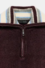 Jersey de punto color bordó con cuello solapa a contraste en tonos beige, gris y azul. Presenta cierre frontal con cremallera metálica, manga larga y puños ajustados.