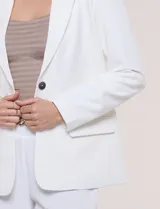 Blazer sastrero blanco de corte recto y estructura entallada, con cuello de solapa en pico, cierre frontal de un botón y bolsillos con solapa.