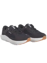 Championes de running Under Armour modelo Charged Versurge, color negro con suela blanca y base de goma color caramelo. Presentan una parte superior de malla con revestimientos de gamuza sintética y logo de la marca en el talón.