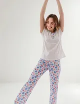 Pijama compuesto por una remera blanca de manga corta con cuello redondo y cartera de botones con ribete estampado, y un pantalón largo con estampado tropical de hojas y sandías sobre fondo blanco.