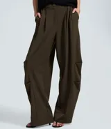 Pantalón sastre de corte barrel, con diseño de piernas anchas y volumen estructurado en los laterales. Presenta pliegues frontales, cintura con elástico en la parte posterior y acabado refinado.