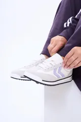 Championes urbanos de diseño moderno, combinan paneles en color blanco y gris claro con detalles en lila en los laterales. Presentan suela plana con una fina línea negra y cordones al tono.