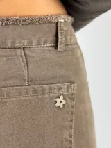 Pantalón de jean beige de corte acampanado con terminación desflecada.