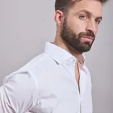 Camisa negra de algodón con cuello clásico, manga larga y cierre frontal con botones. Presenta un logo bordado en el pecho. Corte entallado.