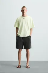 Camiseta de corte relaxed fit, color verde lima pálido, con cuello redondo y manga corta. Presenta un estampado sutil en el pecho.