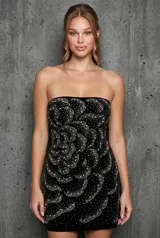 Vestido corto strapless de terciopelo negro, decorado con pedrería formando un diseño floral.