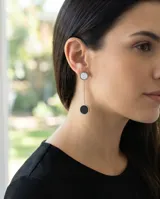 Caravanas colgantes de acero italiano con diseño de doble círculo, uno superior blanco y uno inferior negro, unidos por una cadena fina.