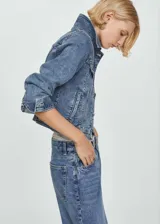 Chaqueta de jean estilo vaquero con cuello de solapa, cierre frontal de botones metálicos, bolsillos con solapa en el pecho y bolsillos laterales. Presenta un diseño corto de corte recto y mangas largas con puños abotonados.