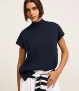 Blusa azul marino de punto texturizado, con cuello alto acanalado y manga corta amplia. Presenta aberturas laterales en la parte baja.