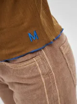 Polera de cuello alto confeccionada en tela rib color blanco, con mangas largas y hombreras. Presenta pespuntes en contraste en las terminaciones del cuello, hombros y puños.