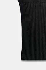 Top de punto negro con cuello redondo, manga sisa, hombreras marcadas y diseño ajustado con rib en el bajo.