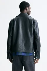 Campera de cuero sintético color negro con cuello camisero, cierre frontal, bolsillo superior con cierre y bolsillos laterales ribeteados.