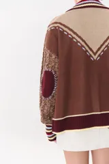 Cardigan de punto con diseño multicolor en tonos marrones, bordó y detalles en amarillo y celeste. Presenta cuello tipo polo, cierre frontal con botones, bolsillos aplicados en el frente y mangas con trama trenzada y coderas bordadas.