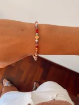 Pulsera elástica compuesta por pequeñas cuentas de cristal facetado en tonos cálidos y neutros, con un dije central cuadrado en tono dorado.