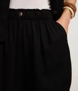 Short runner de viscolino, con cintura elástica, botón decorativo y bolsillos laterales. Presenta un corte evasé holgado con bajo redondeado.