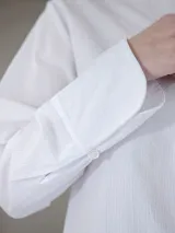 Camisa de corte recto y tejido semitransparente, con cuello mao y cierre frontal oculto por tapeta. Presenta mangas largas con puños anchos y un diseño minimalista.