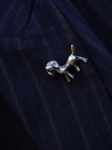 Pin metálico con forma de perrito, acabado plateado con detalles esculpidos.