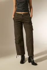 Pantalon cargo de algodón color gris oscuro, de tiro alto y corte recto. Presenta bolsillos laterales tipo cargo y una hilera de ojales metálicos decorativos a lo largo de la pierna derecha.