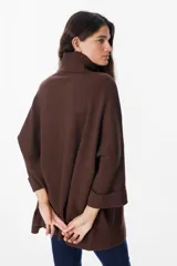 Sweater de tejido de punto suave en color beige, con silueta holgada, cuello alto y mangas tres cuartos con puños definidos.