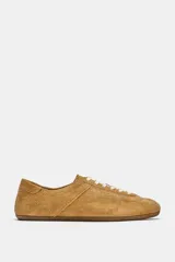 Zapatilla deportiva de piel en color marrón tostado, con diseño de perfil bajo, detalles de pespuntes y cierre mediante cordones.