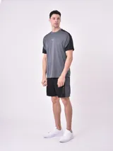 Remera deportiva gris oscuro con mangas cortas negras y logo pequeño estampado en el pecho.