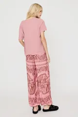 Remera rosada de manga corta con estampado frontal de estilo bohemio que incluye un corazón sagrado, mariposas, jaguares y detalles en strass.