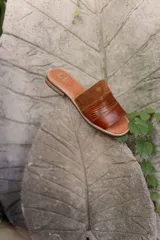 Sandalias planas de cuero marrón con tira ancha sobre el empeine. La plantilla es de cuero con la inscripción "LE".