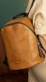 Mochila de tamaño mediano confeccionada en símil cuero color suela, con cierre principal de gran capacidad, asa de mano superior y correas regulables. Incluye bolsillo oculto en la parte trasera y detalles metálicos.