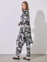 Cardigan largo de satén plisado con estampado abstracto en blanco y negro, marca Cyrus. Presenta aberturas laterales.