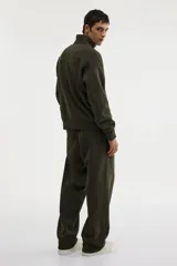 Buzo de tejido pesado de mezcla de algodón con interior cepillado suave, color verde oliva. Modelo con hombros caídos, cuello elevado con medio cierre metálico y puños y bajo en punto acanalado.