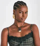 Collar largo con cordón negro y colgante de forma orgánica, mitad negro y mitad dorado. El colgante está hecho de poliuretano, zinc y hierro.