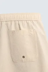 Bañador largo de hombre color rosa pálido con textura seersucker. Presenta cintura elástica ajustable con cordón blanco, bolsillos laterales y un bolsillo trasero de plastrón.