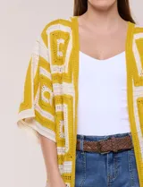 Cardigan largo confeccionado en tejido de punto calado estilo crochet, de color amarillo y blanco, con diseño geométrico de cuadrados, mangas amplias tipo kimono y corte abierto al frente.