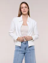 Camperita corta blanca de punto elastizado, con cuello camisero, cierre frontal completo y mangas largas con puños anchos abotonados.